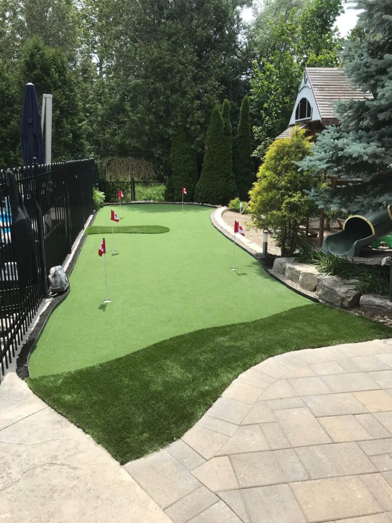 installed putting green in a backyard in the south end of Guelph, ON next to an inground pool surrounded by trees