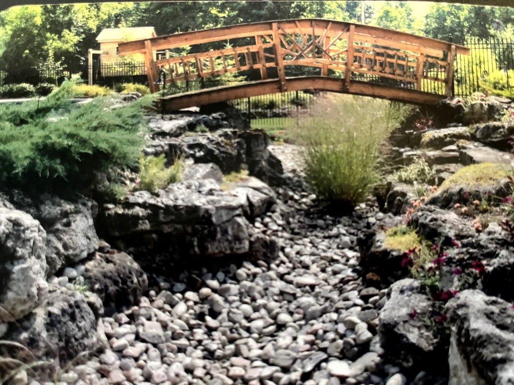 Rockery Retaining wall with a curved wooden walkway bridge
