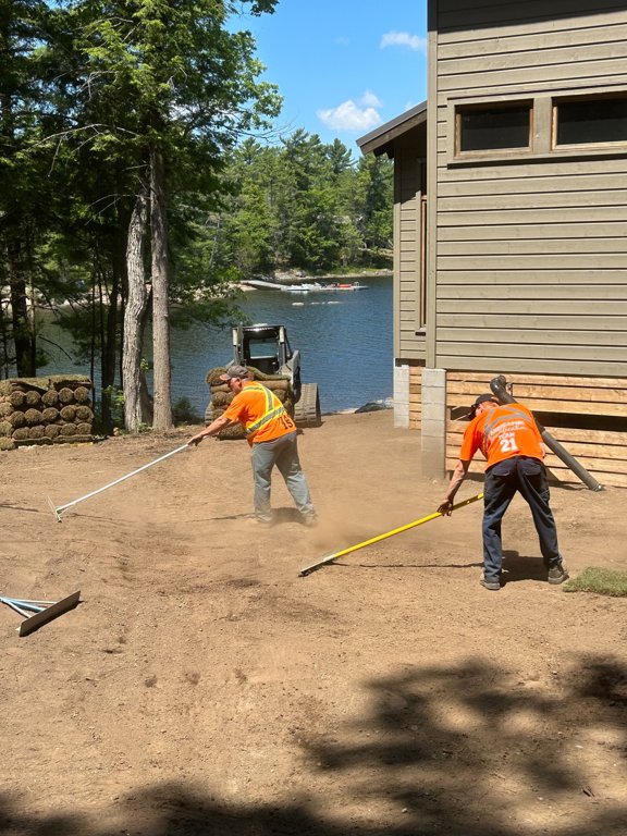 Jason and Eric palmer hand grading soil around a cottage